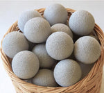 Palline di cotone luminose grigio chiaro in cesto vimini, ghirlanda tinta unita neutra
