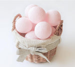 Palline di cotone luminose rosa in cestino vimini con fiocco, ghirlanda per cameretta