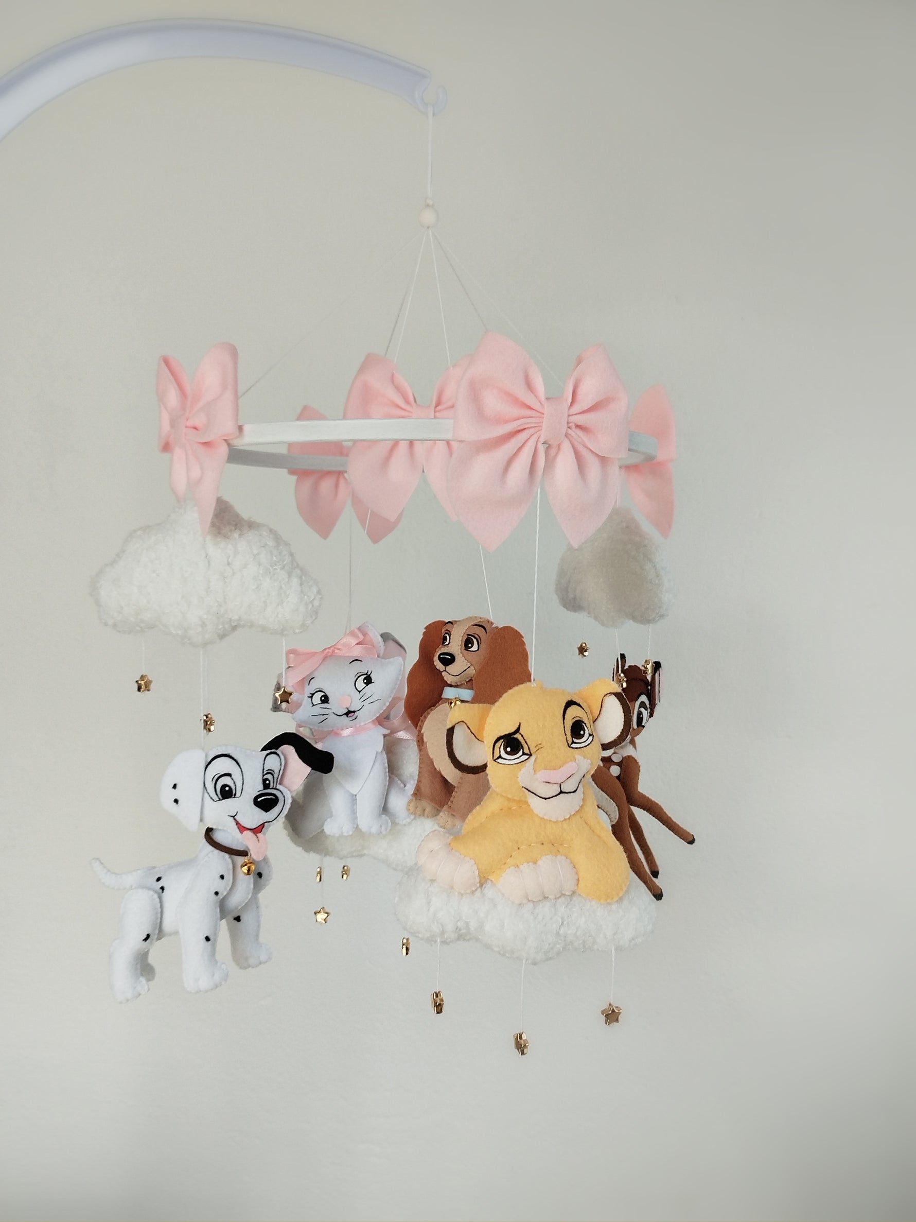 Giostrina musicale appesa con Simba giallo, dalmata bianco, gatta Minou, Lilli marrone, Bambi e grandi fiocchi rosa.