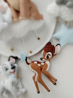 Dettaglio giostrina culla Disney con Bambi marrone miele, macchie bianche e farfalla azzurro polvere, regalo nascita