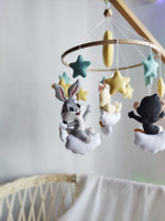 Giostrina musicale artigianale in feltro con Baby Looney Tunes, luna e stelle su struttura in legno naturale.