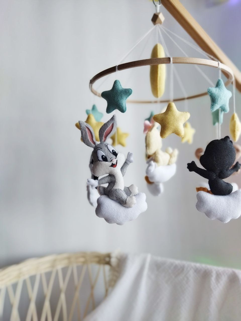 Giostrina musicale artigianale in feltro con Baby Looney Tunes, luna e stelle su struttura in legno naturale.