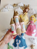 Dettaglio giostrina culla con castello in feltro rosa antico e tetti oro glitter, nuvole bianche e principesse Disney