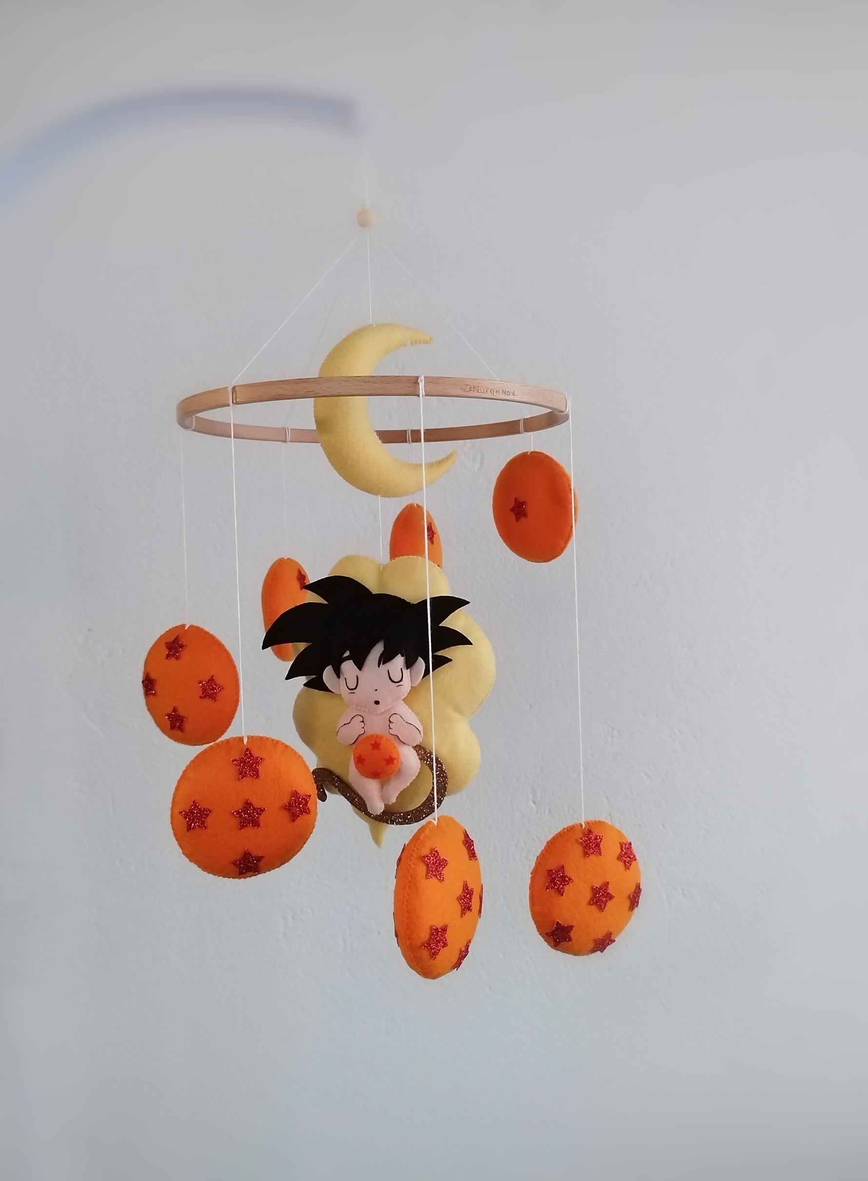 Giostrina culla Dragon Ball con Goku neonato, nuvola giallo limone e sfere del drago arancione brillante in feltro