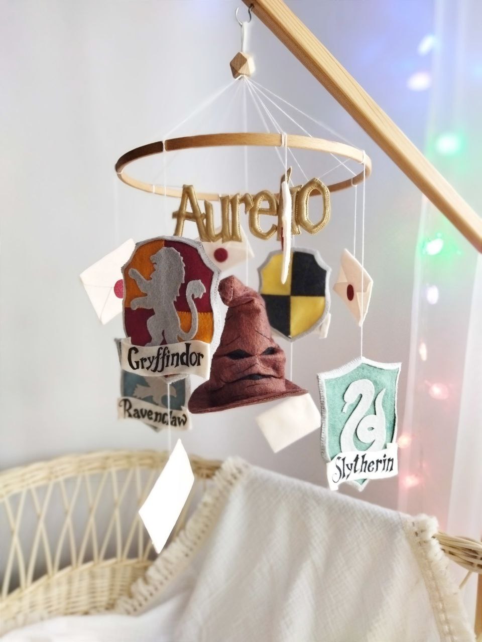 Giostrina culla in legno Harry Potter con nome Aurelio, stemmi Grifondoro, Serpeverde, Corvonero e Tassorosso in feltro.