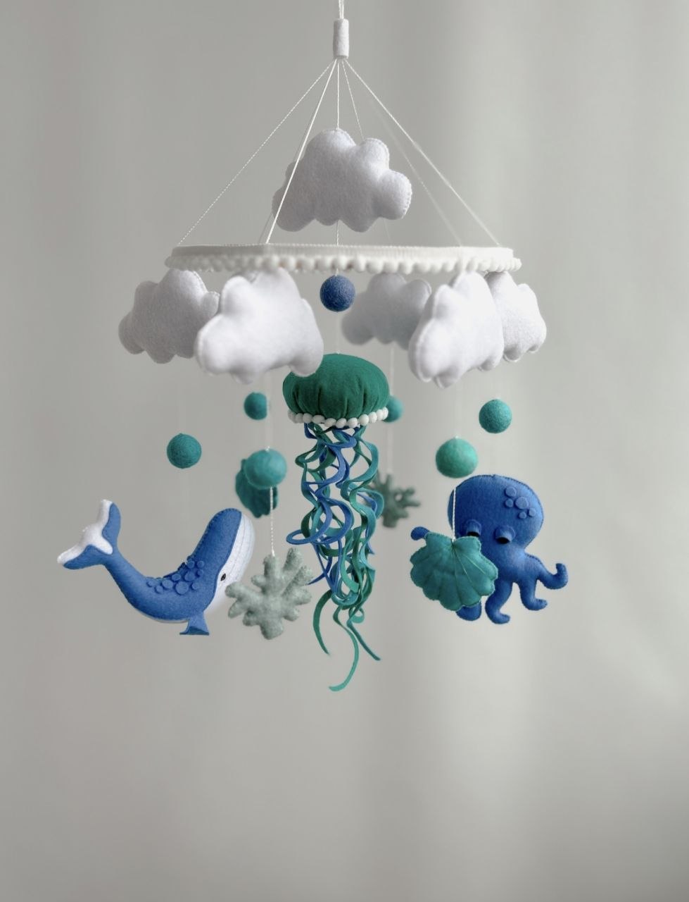 Balena blu, polpo con conchiglia verde acqua e medusa petrolio sotto nuvole bianche, giostrina culla mondo marino in feltro