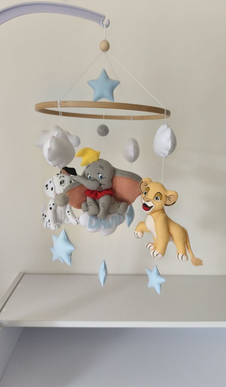 Giostrina musicale cucita a mano vista di lato: Simba, Dumbo e dalmata con stelle azzurre e palloncini bianchi