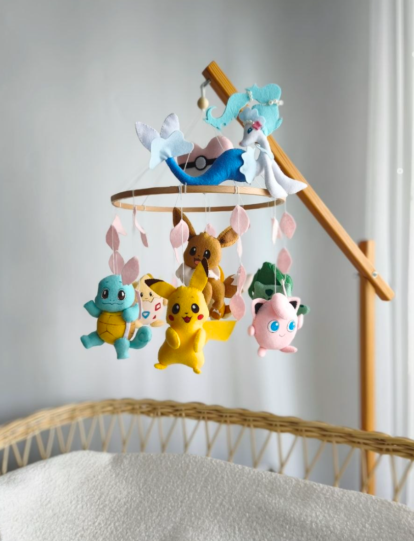 Giostrina neonato Pokémon fatta a mano con Pikachu, Squirtle, Jigglypuff e Primarina appesi sopra la culla.