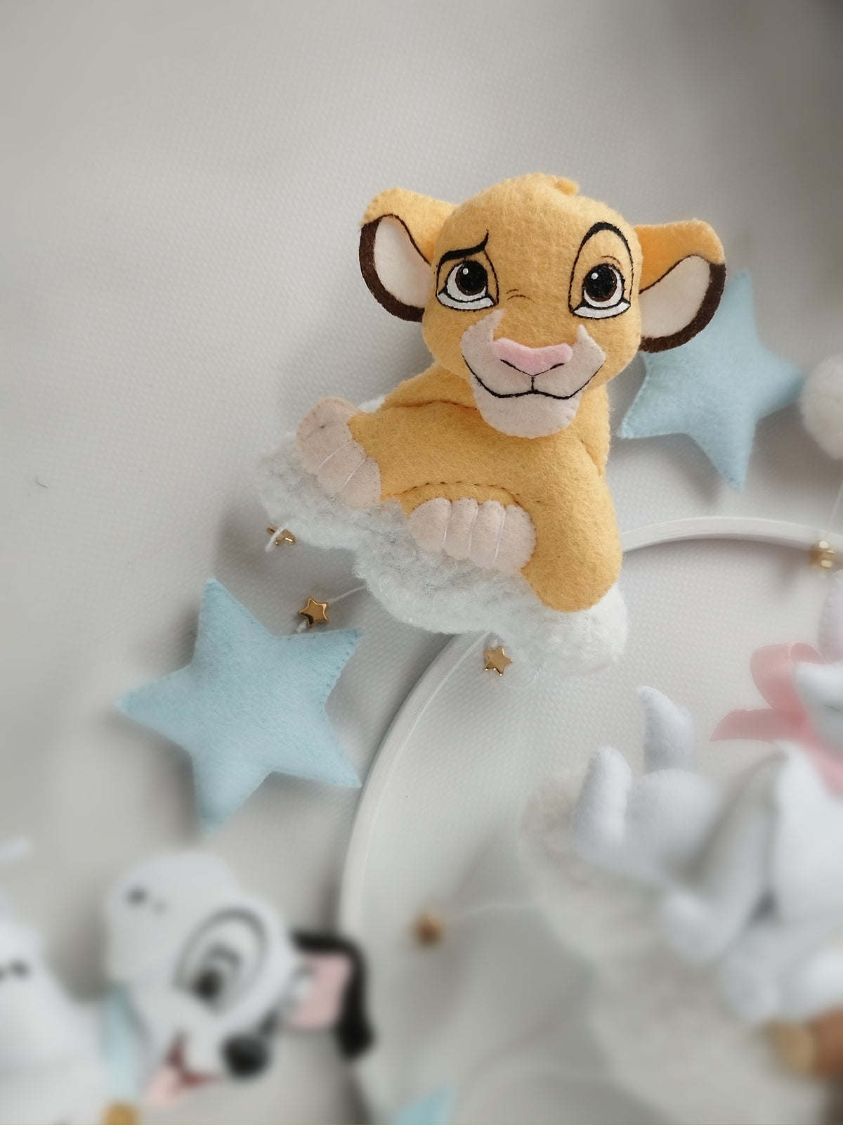 Dettaglio giostrina culla Disney con Simba giallo senape su nuvola bianco latte e stelle azzurro polvere, regalo nascita