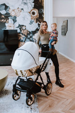 Mamma con bambino e passeggino Kunert Ivento Glam navicella bianco perla struttura dorata, ruote cerchi oro, lifestyle interior