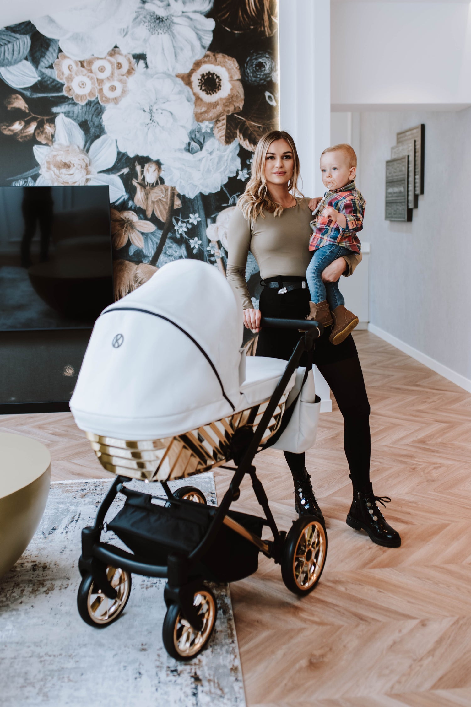 Mamma con bambino e passeggino Kunert Ivento Glam navicella bianco perla struttura dorata, ruote cerchi oro, lifestyle interior