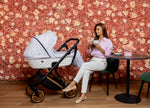 Passeggino Kunert bianco oro con navicella mamma seduta sfondo floreale rosa