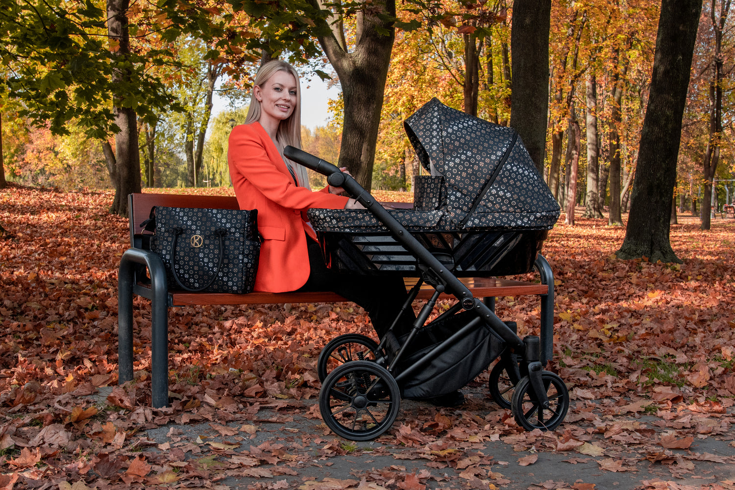 Passeggino Kunert Black Style navicella nera fantasia con borsa mamma seduta in parco foglie autunno
