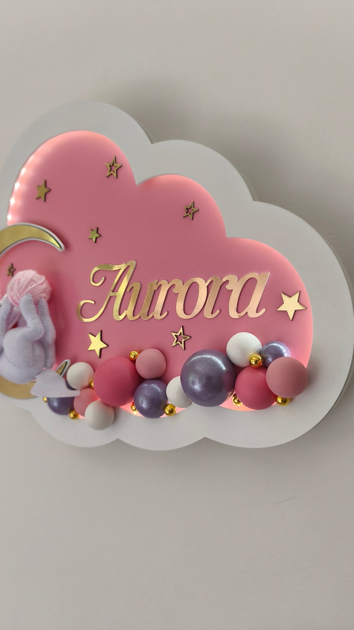 Dettaglio di luce notturna rosa a forma di nuvola con una fila di palline decorative fatte a mano alla base