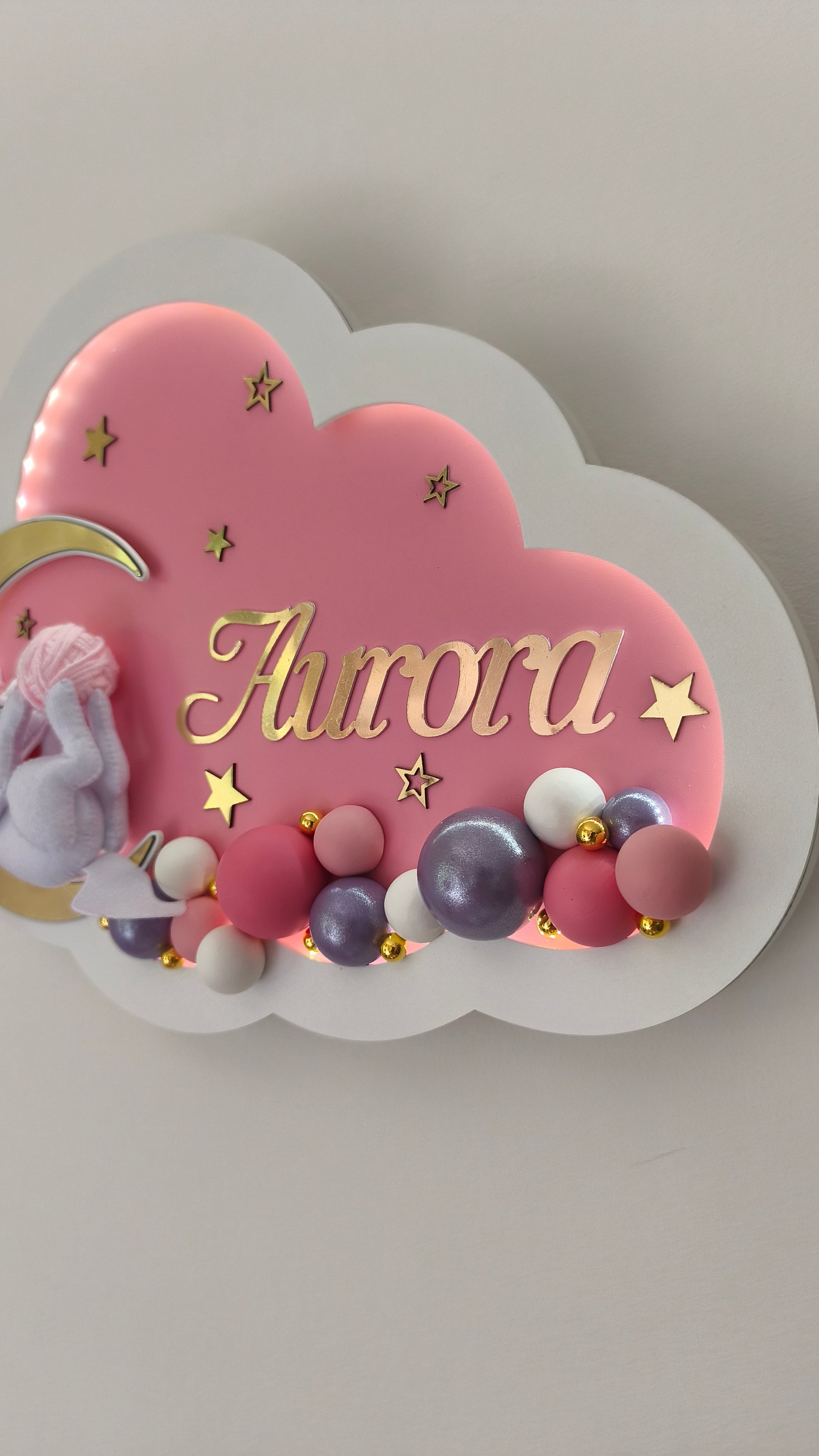 Dettaglio di luce notturna rosa a forma di nuvola con una fila di palline decorative fatte a mano alla base