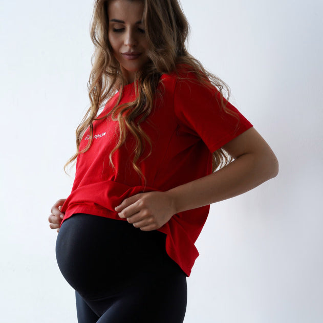 Leggings premaman neri morbidi sul pancione, abbinati a una t-shirt rossa