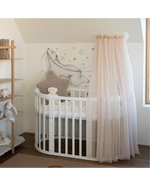 Lettino ovale bianco con baldacchino rosa cipria in cameretta neonato stile nordico
