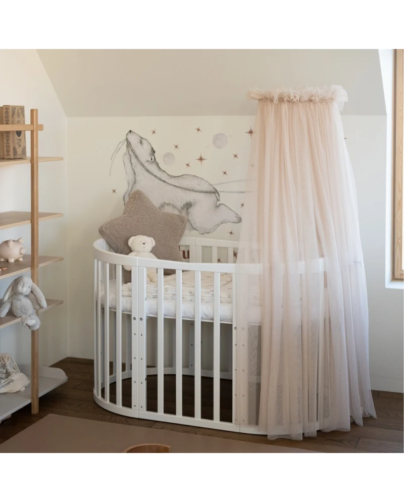 Lettino ovale bianco con baldacchino rosa cipria in cameretta neonato stile nordico