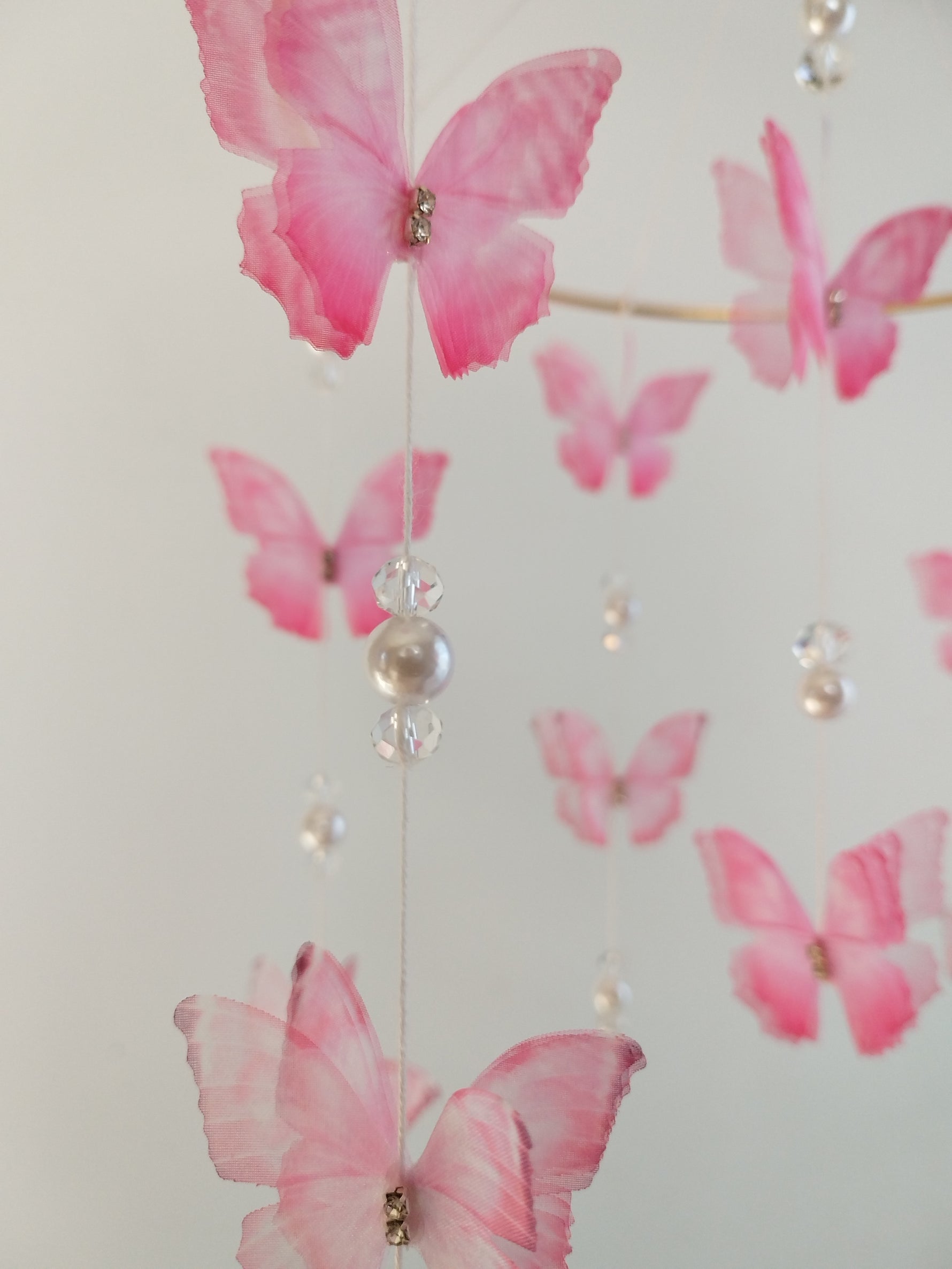 Dettaglio giostrина culla farfalle organza rosa sfumata con perla bianca cristalli e strass artigianale