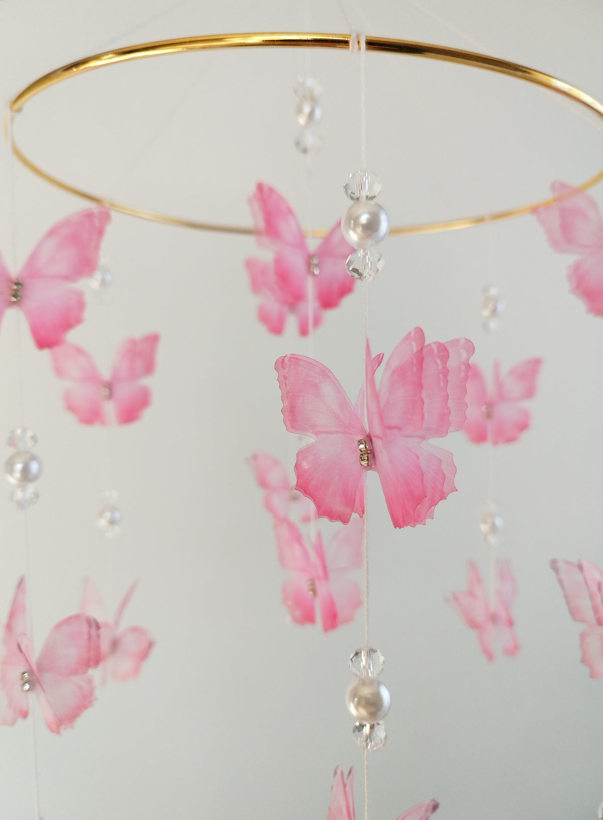 Dettaglio mobile culla farfalle in organza rosa con strass perline bianche e cristalli anello dorato