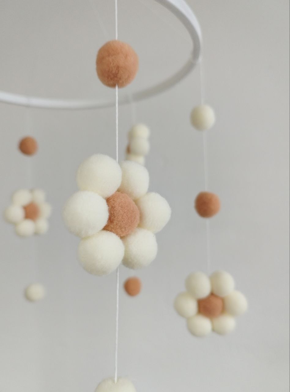 Dettaglio fiore pon pon feltro panna con centro caramello e palline pendenti giostrина culla artigianale