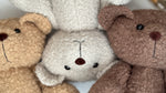 Tre orsetti di peluche in tessuto riccio nei colori beige, panna e marrone scuro per neonati