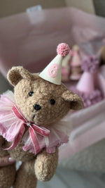 Primo piano di un orsetto di peluche con cappellino rosa numero 6 per il complimese del neonato