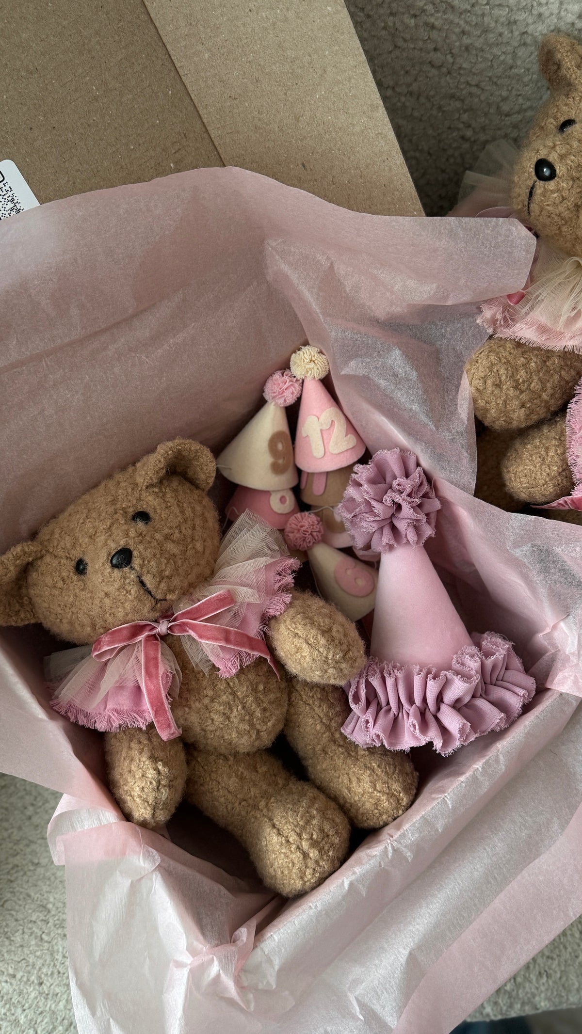 Dettaglio orsetto di peluche in scatola con carta velina rosa e cappellini per foto mesi del neonato