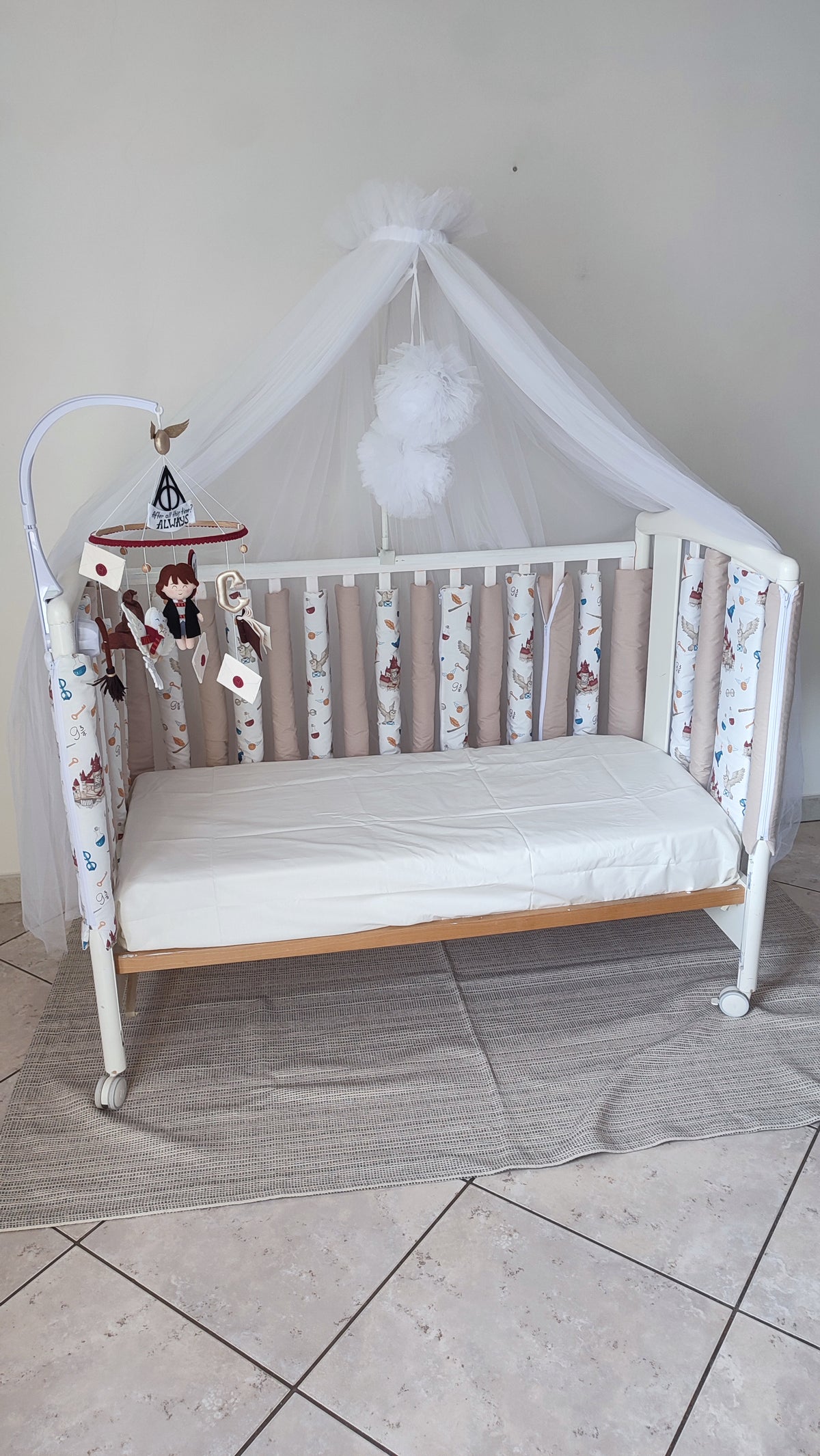 Paracolpi americani per lettino neonato Harry Potter su fondo bianco, toni beige e bordeaux, abbinati a baldacchino in tulle bianco e mobile musicale