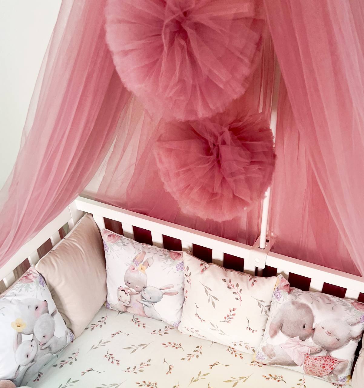 Dettaglio pompon tulle rosa baldacchino con cuscini coniglietti, paracolpi lettino neonata fiori delicati