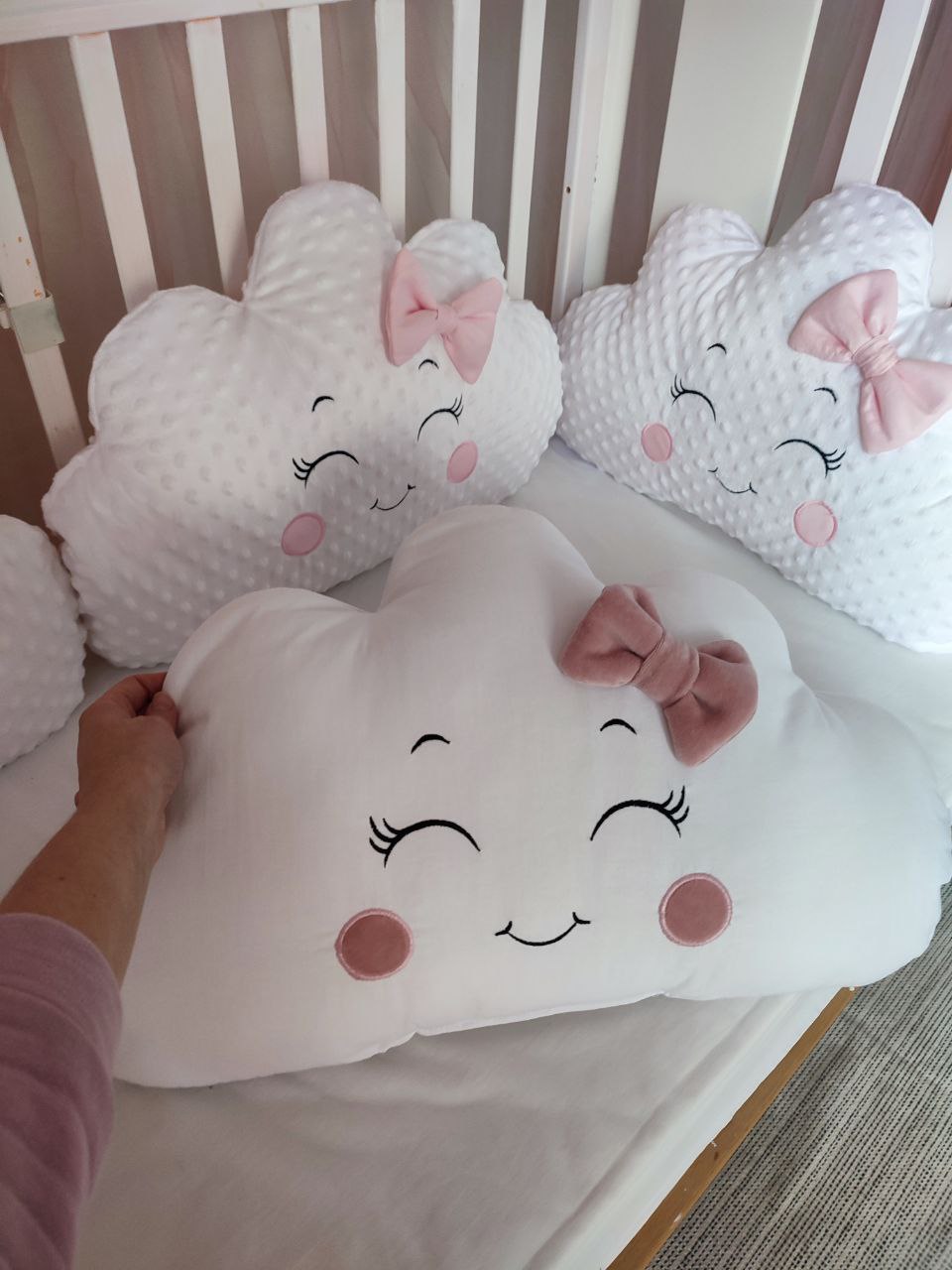 Paracolpi lettino a cuscini nuvola bianchi in tessuto minky e liscio con viso ricamato e fiocchetti rosa per neonata.
