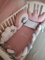 Set culla con paracolpi a treccia grigio e rosa, cuscini a corona e nuvoletta e riduttore arcobaleno con stelline.