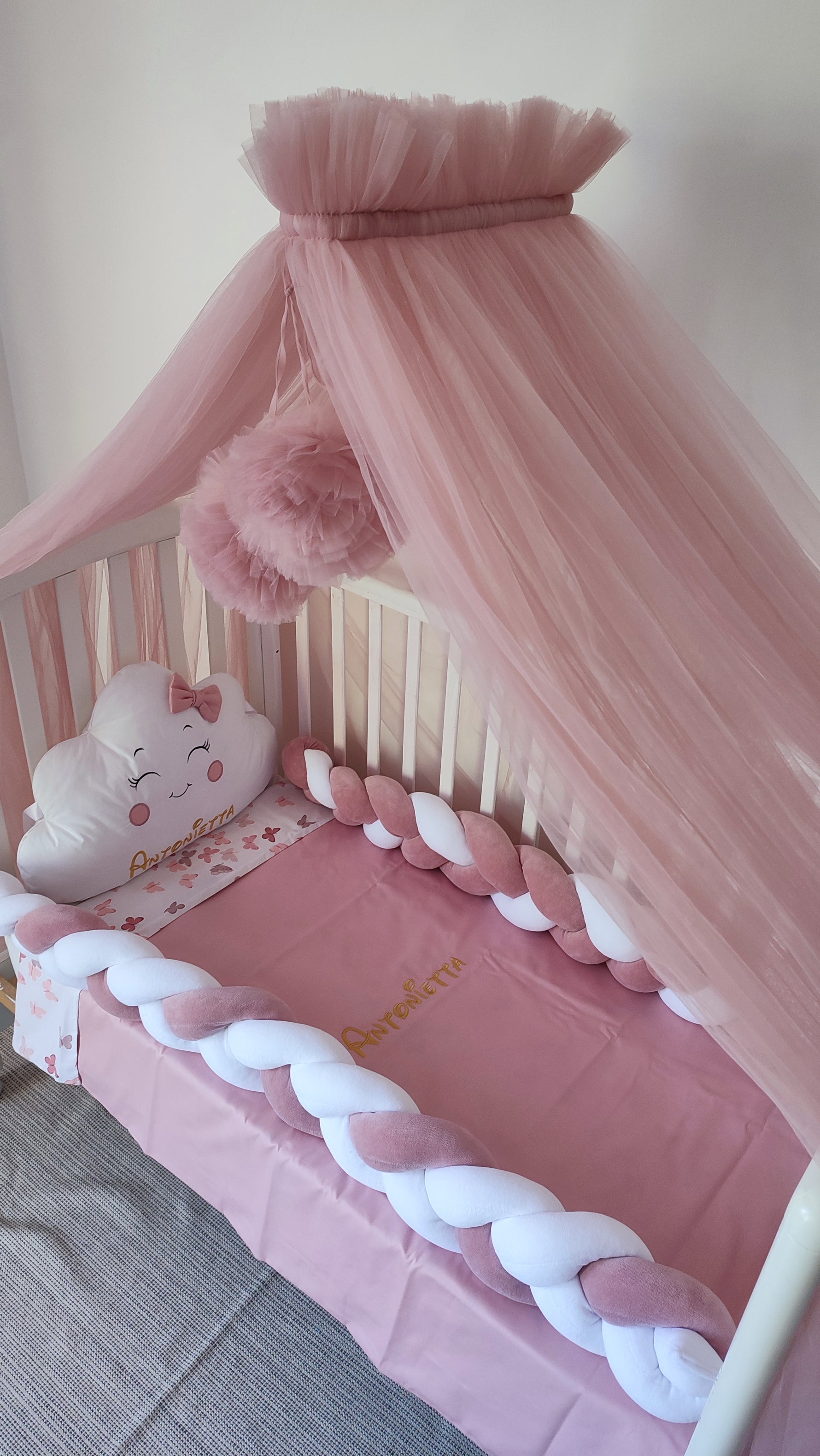 Paracolpi lettino neonata a treccia rosa antico e bianco con cuscino nuvola bianco con fiocco e lenzuola rosa con nome ricamato