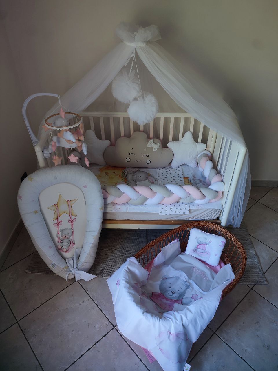 Paracolpi a treccia rosa grigio e bianco con cuscino nuvola beige stelle bianche riduttore lettino e culla in vimini neonata.