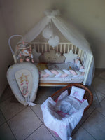 Paracolpi a treccia rosa grigio e bianco con cuscino nuvola beige stelle bianche riduttore lettino e culla in vimini neonata.
