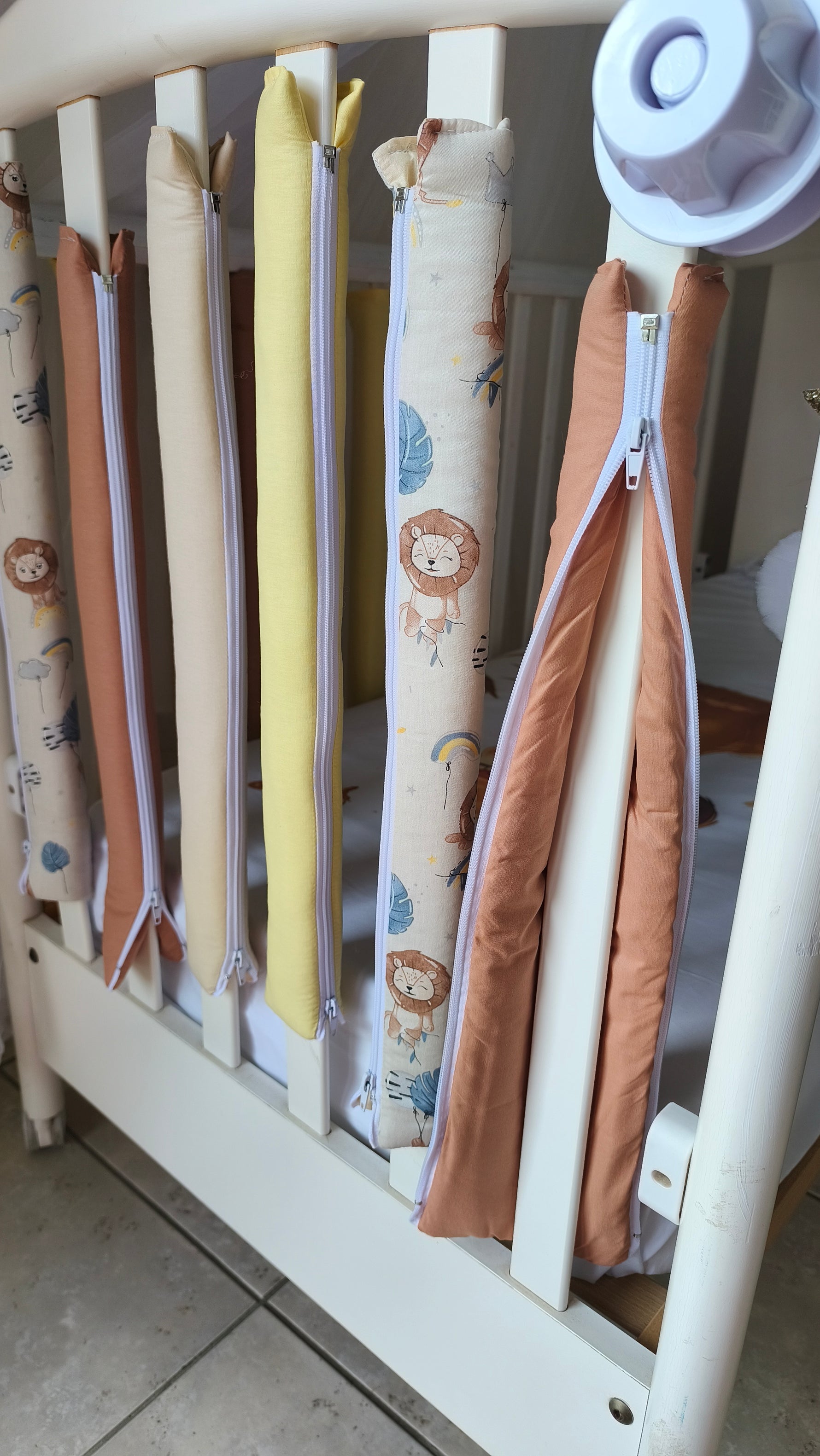 Dettaglio paracolpi tubolari con cerniera bianca, tessuto cotone fantasia leoncini beige e tinta unita terracotta e giallo