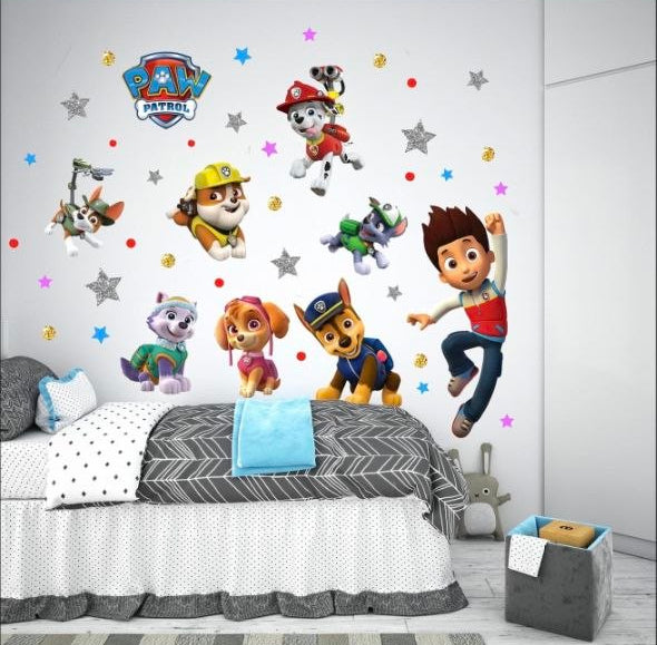  Parete bianca di una cameretta decorata con adesivi murali di Ryder e i cuccioli Paw Patrol sopra il letto.