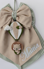Dettaglio ravvicinato di fiocco nascita beige e verde salvia con mongolfiera in pannolenci e piccolo leone personalizzato