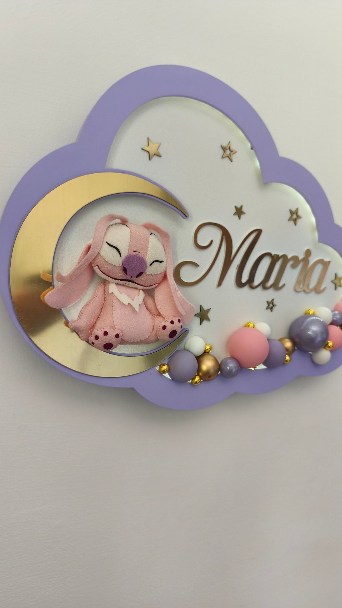 Primo piano di Angel di Stitch su luna oro con nome intagliato Maria, stelline e palloncini lilla decorativi.