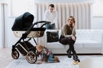 Passeggino trio Kunert Ivento nero con scocca geometrica oro metallizzato in un moderno salotto con famiglia