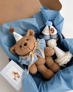 Peluche orso con colletto in tulle azzurro, cappellini numerati e biglietto abbinato