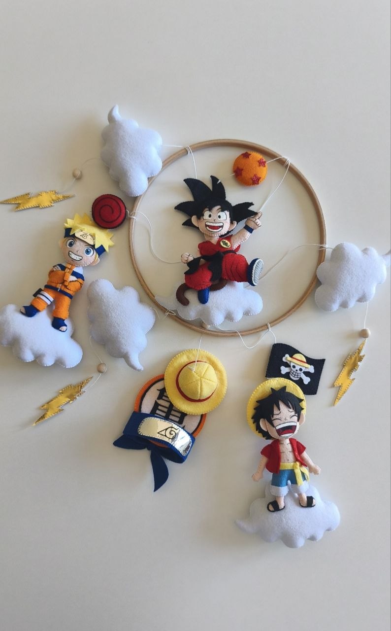 Personaggi in feltro della giostrina anime: Goku, Naruto e Luffy su nuvole con fulmini e simboli