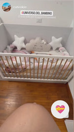 Set culla con paracolpi a treccia rosa e grigio, due cuscini a stella, una nuvoletta beige e copertina con stampa orsetto.