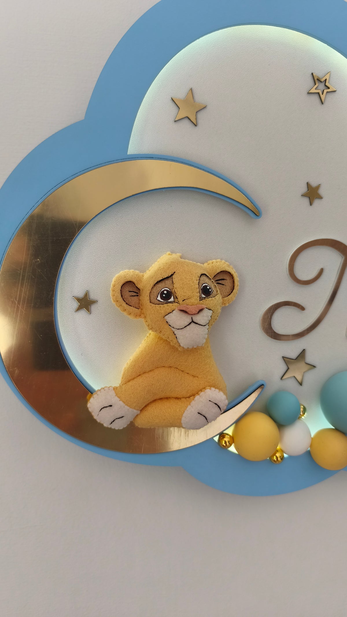 Primo piano peluche cucciolo di leone su luna, perline senape e turchesi