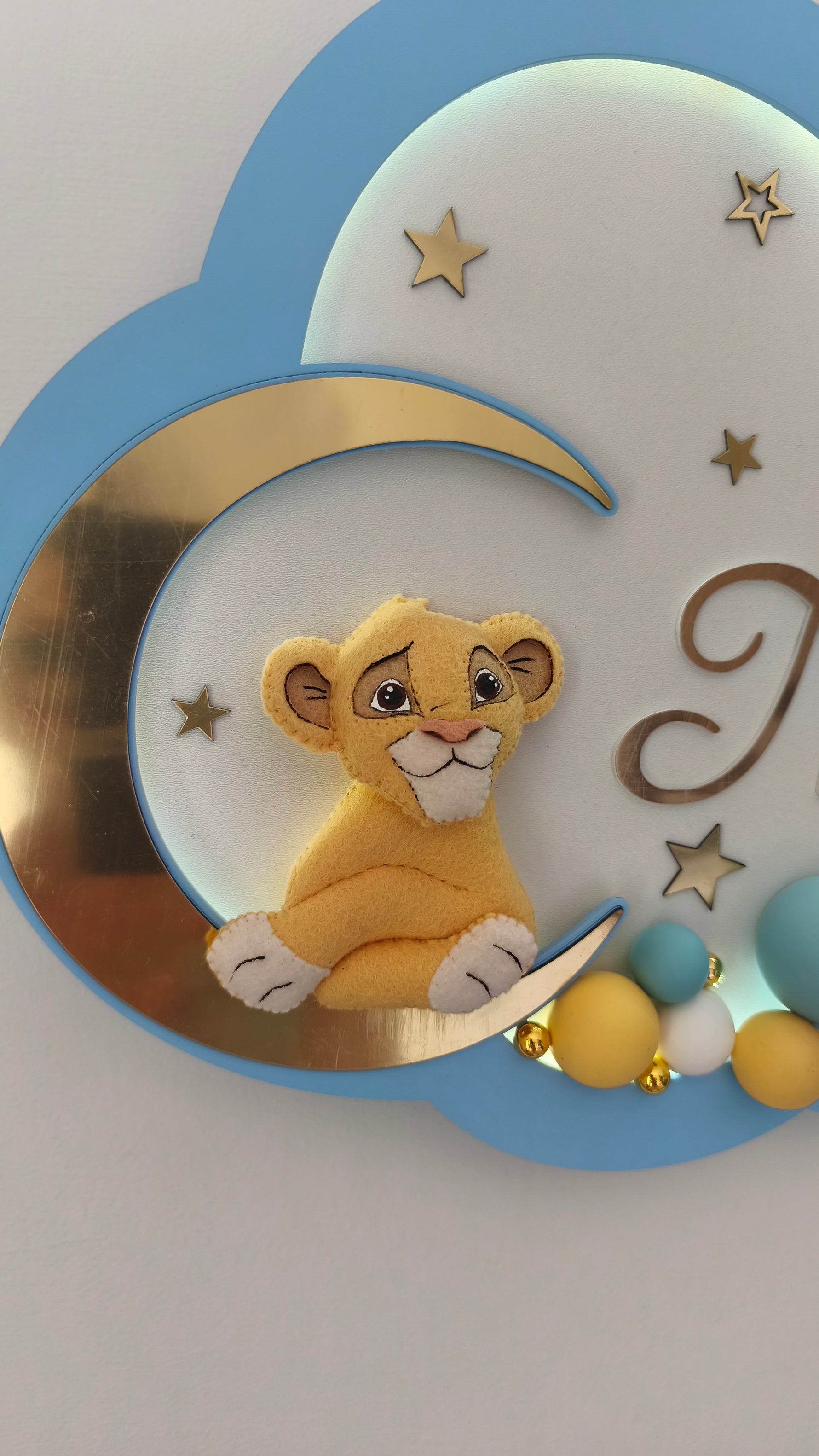 Primo piano peluche cucciolo di leone su luna, perline senape e turchesi
