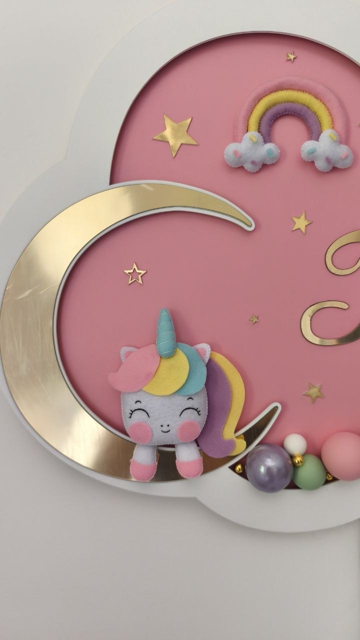 Primo piano peluche unicorno pastello su luna, arcobaleno e stelle dorate