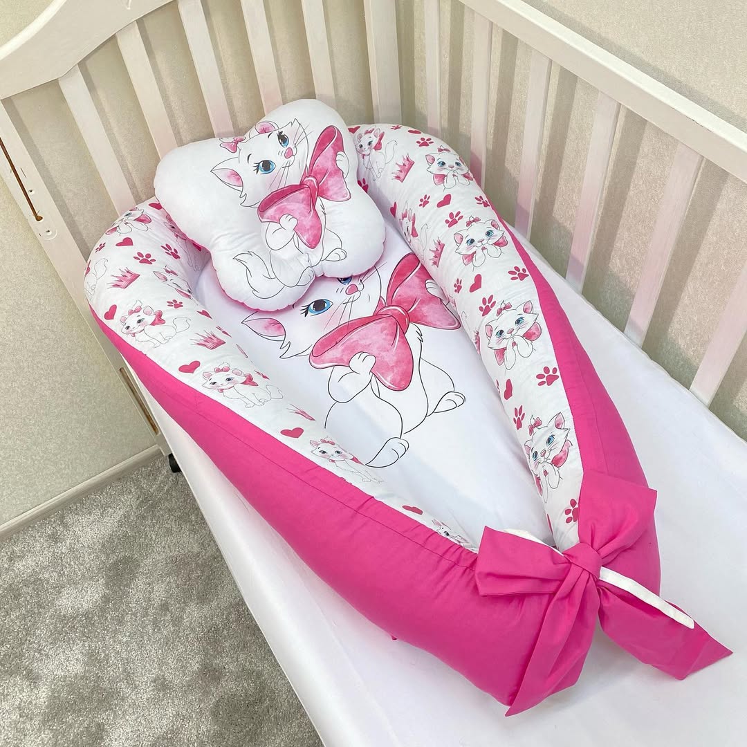 Riduttore nido neonato fucsia posizionato nel lettino a sbarre in legno, baby nest con cuscino coordinato 