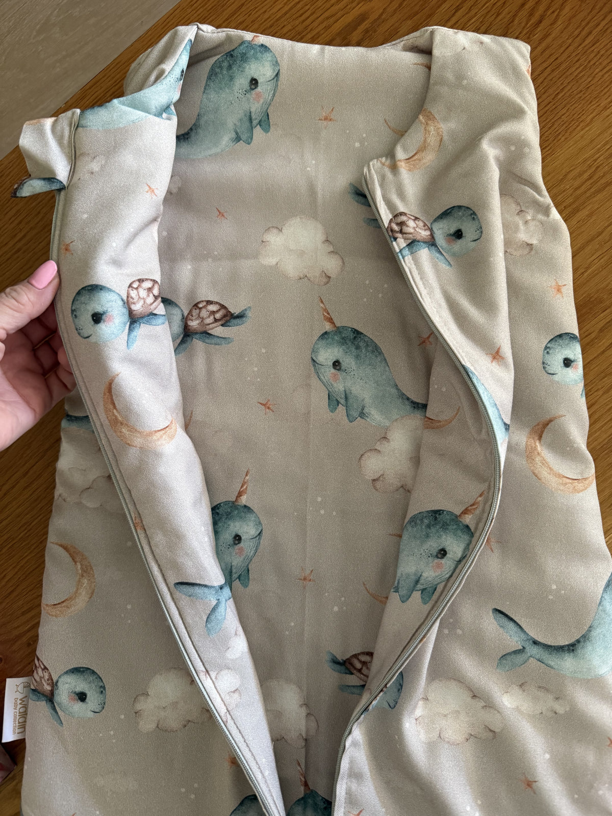 Sacco nanna in bamboo per neonati con fantasia narvali, tartarughe e luna su fondo beige, con zip laterale visibile, ideale per dormire sicuro in culla