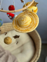 Dettaglio Saturno in feltro cucito a mano per giostrina culla tema spazio, con anelli e stelle dorate per cameretta neonato
