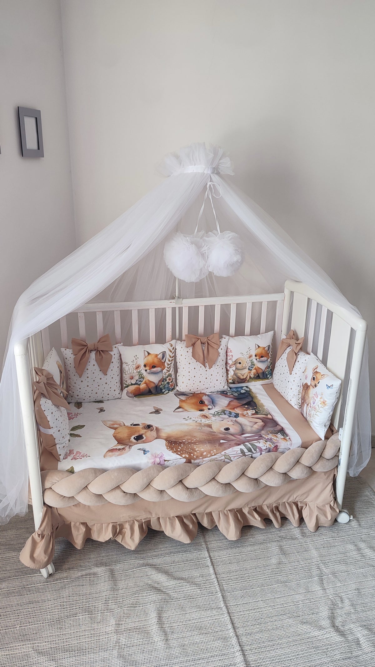 Set lettino neonato beige con paracolpi a treccia, cuscini a fiocco tema bosco e baldacchino in tulle bianco